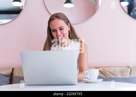 Happy female freelancer using laptop in cafe Stock Photo