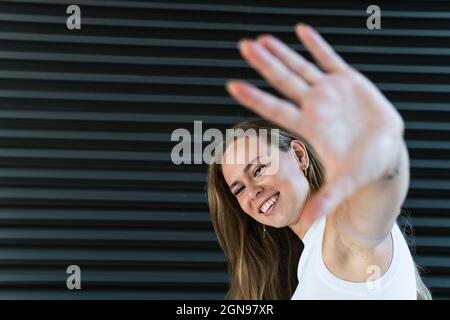 Cheerful businesswoman showing palm in front of black wall Stock Photo