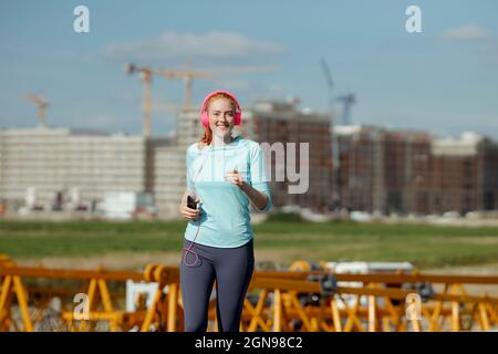 Smiling woman jogging at construction site Stock Photo