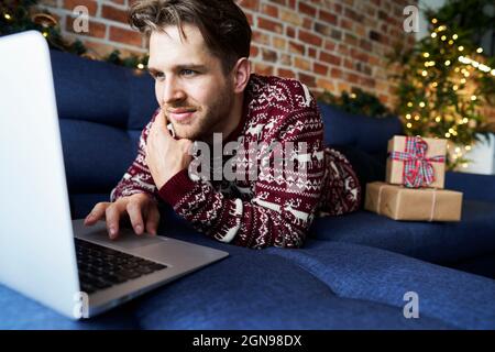 Young man using laptop while relaxing on sofa Stock Photo