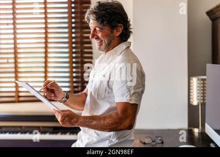 Smiling male freelancer writing in document at home office Stock Photo