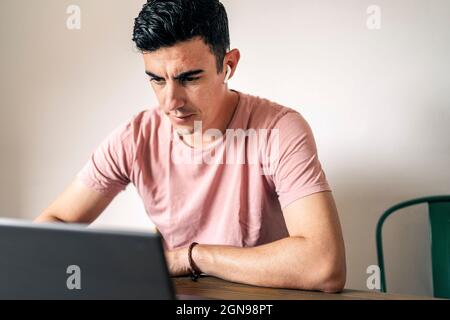 Freelance in casual clothes browsing laptop working on a project Stock Photo