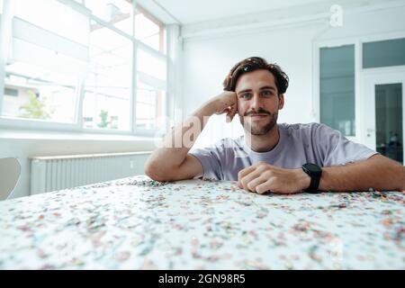 Smiling man leaning on table with confetti Stock Photo