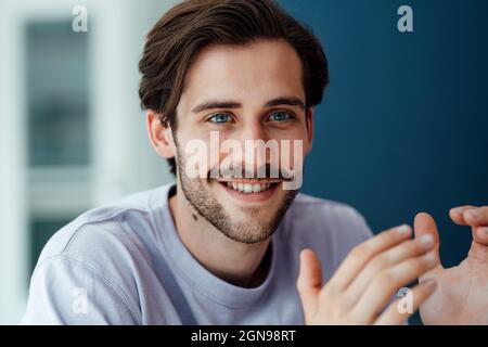 Smiling young man gesturing at home Stock Photo