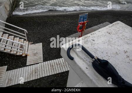 View of a beach and waves of the Black Sea from an embankment in the center of Sochi city in rainy weather, Russia Stock Photo