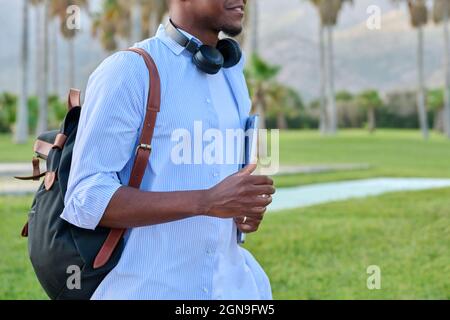 Outdoor portrait of young man with laptop headphones and backpack Stock Photo