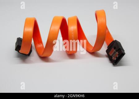 Red, black and orange SATA cable for connecting HDD or SSD to the computer. Motherboard connection cable to storage hardware. Data cable. Stock Photo