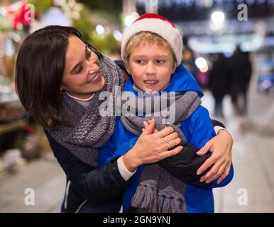 Happy tween boy with mom during shopping at Christmas fair Stock Photo