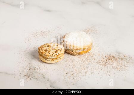 two alfajores decorated with sugar on a textured table, detail of sweet food in studio, delicious dessert Stock Photo