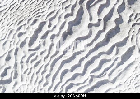 Gray-white texture background of Pamukkale calcium travertine in Turkey, pattern of diagonal waves, close-up. Stock Photo