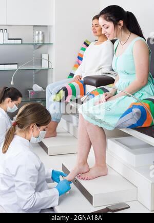 happy women getting pedicure by professional in beauty salon Stock Photo