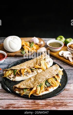 Mexican quesadilla made with tortilla and stuffed with pork rinds or mushrooms, squash blossom, oaxaca cheese, chili slices or salsa in Puebla City, M Stock Photo