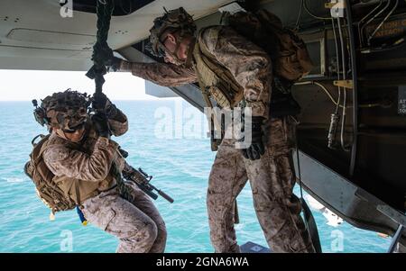 210921-M-OY155-1091 ARABIAN GULF (Sept. 21, 2021) Marine Corps Cpl. Kameron Helm, right, an assistant team leader assigned to Bravo Company, Battalion Landing Team 1/1, 11th Marine Expeditionary Unit (MEU), observes Marines conducting fast-rope training from an MV-22B Osprey attached to to Marine Medium Tiltrotor Squadron (VMM) 165 (Reinforced), 11th MEU, aboard the amphibious assault ship USS Essex (LHD 2). Essex and the 11th MEU are deployed to the U.S. 5th Fleet area of operations in support of naval operations to ensure maritime stability and security in the Central Region, connecting the Stock Photo