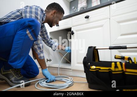 Plumber Drain Cleaning Services In Kitchen. Unclog Blocked Pipe Stock Photo