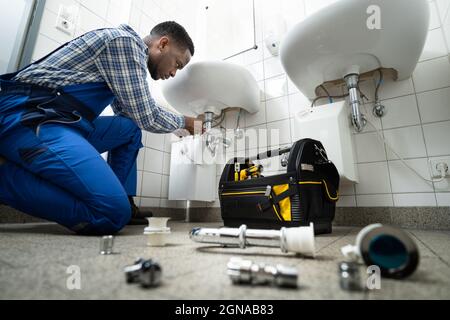 Plumber Fixing Pipe In Bathroom. Plumbing Maintenance In Bathroom Stock Photo