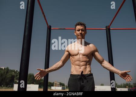 fitness, sport, training and lifestyle concept - young man exercising on horizontal bar on the beach Stock Photo