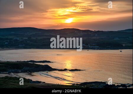 Sun setting behind the mountains at Culdaff beach in County Donegal Ireland Stock Photo