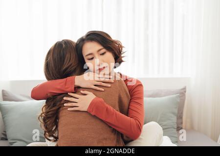 Side view of two sad good friends embracing in a bedroom in a house interior Stock Photo