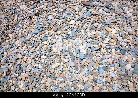 Abstract background of mutlicolored pebbles on the shore from above. Seashore, summer, vacation, beach background photo. Stock Photo