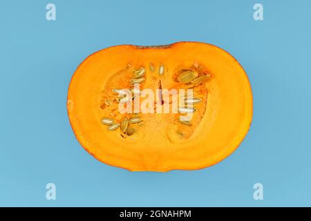 Open ''Red Kuri' squash, also called 'Hokkaido' squash', showing vegetable meat and seeds inside on blue background Stock Photo