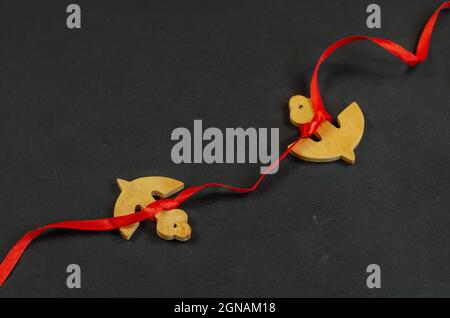 Two wooden anchors tied with red ribbon. Anchor figures on black Stock Photo