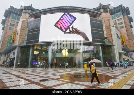 Beijing, China. 24th Sep, 2021. People walk in front of an iPad Mini advertisement on a large screen at an apple store in Wangfujing. On September 24, 2021, the first batch of iPhone 13 series mobile phones are officially launched to be sold worldwide. (Photo by Sheldon Cooper/SOPA Images/Sipa USA) Credit: Sipa USA/Alamy Live News Stock Photo