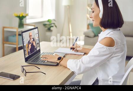 Senior business woman sitting at home watching business training or online webinar on laptop. Stock Photo
