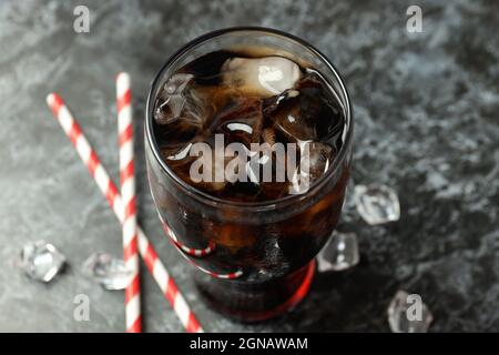 Glass of cola, ice and straws on black smokey background. Stock Photo