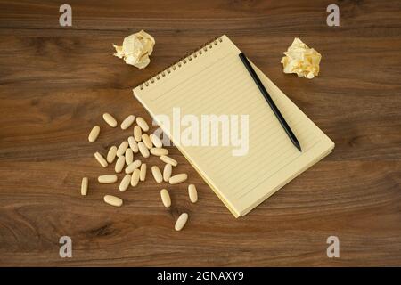 Suicide idea concept. Writing pad, pencil  and the pills on the wooden table. Stock Photo