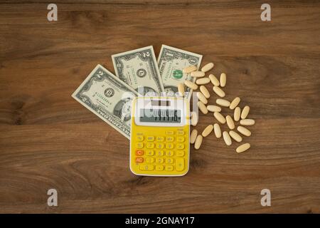Suicide idea. Pills, money and calculator on a wooden background top view. Paid medicine, financial distress idea concept. Stock Photo