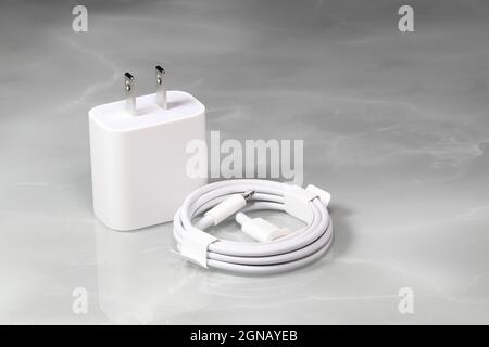 White charger adapter and white USB cable on a white background, New Charger and cable connector for gadgets isolated on a white background. The conce Stock Photo