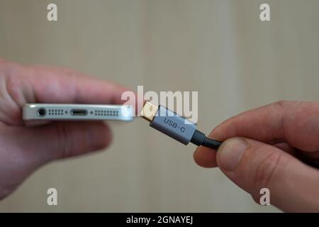 STANBUL TURKEY -27 September, 2021: trying to put type-c on iphone. hand holding type c or usb-c and iphone. Stock Photo