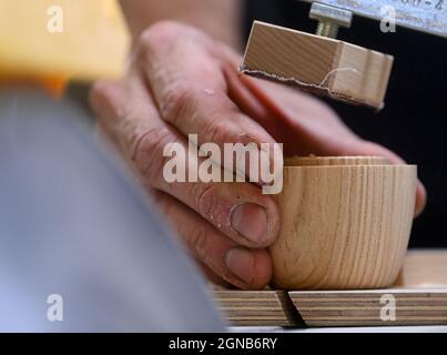 22 September 2021, Saxony, Seiffen: Sven Kuschke saws components for an Angela Merkel smoking figure in the workshop of Seiffener Volkskunst in Seiffen. At the end of her chancellorship, the politician is now also available as a smoked figure from the Erzgebirge and is proving to be a real bestseller at home and abroad. The outgoing chancellor comes in the typical posture with Merkel rhombus and optionally in a blazer in pink, turquoise or purple. The pilot series is already sold out, the next copies will be delivered in February 2022. The Merkel figure is to be the prelude to a series of cele Stock Photo