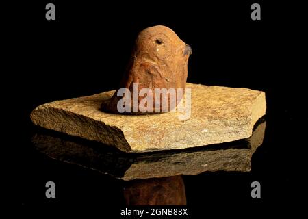 Ceramic bird on flat rock isolated on black glass Stock Photo