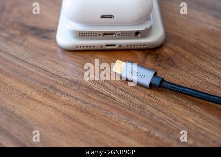 Trying to put type-c  or usb-c on mobile phone. Smartphones headphones and type c cable on the table Stock Photo