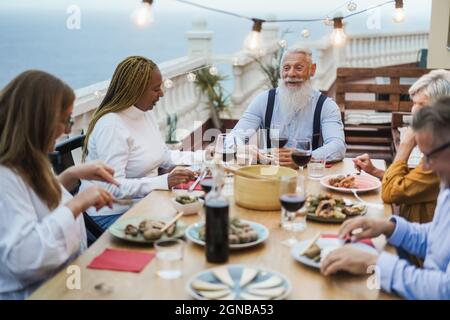 Senior friends having fun at patio dinner party - Focus on hipster male face Stock Photo