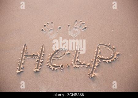 HELP written in the damp sand on a beach Stock Photo