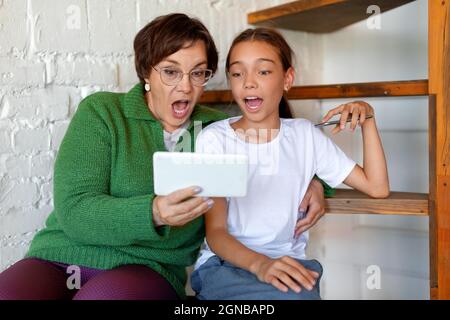 Amazed grandmother and granddaughter with smartphones. The concept of modern technologies. Stock Photo