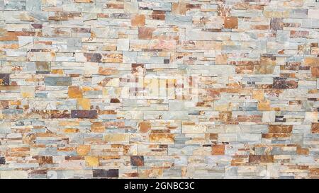 Stone wall made of narrow stones in yellow and brown tones Stock Photo
