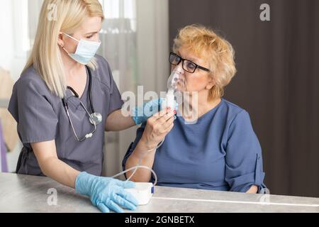 Young Female Doctor Holding Oxygen Mask Over Senior woman Patient's Face. Stock Photo