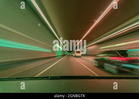 Highspeed blurred background, driving fast through a tunnel overtaking a car with light blurry long exposure effects Stock Photo
