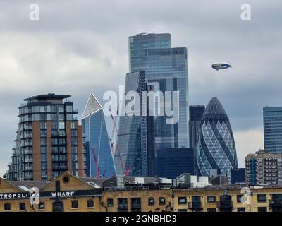 LONDON, UNITED KINGDOM - Sep 07, 2021: Goodyear blimp flied over skyscrapers in the City of London, England Stock Photo