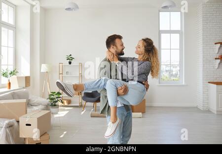 Romantic portrait of joyful and satisfied young couple in love moving to their new home. Stock Photo