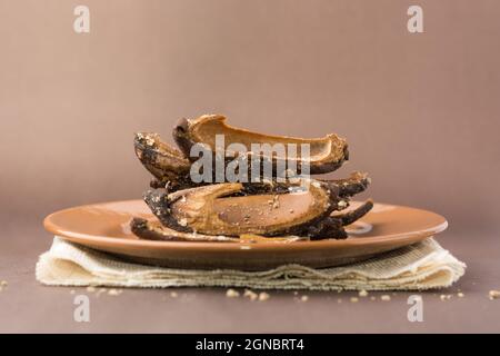 sun dried salted raw mangoes, preserved slices of fruit free from moisture on a plate, isolated on brown background Stock Photo