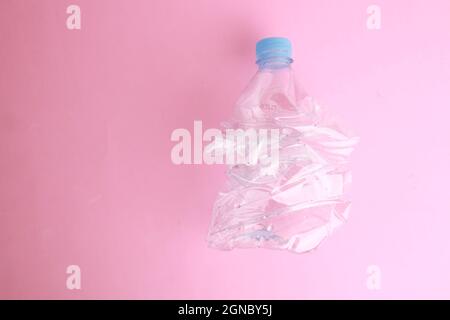 Empty plastic water bottle scaled for recycling on a pink surface Stock Photo