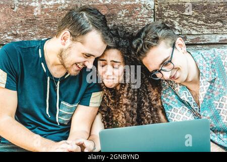 Multiracial friends having fun with laptop during a video call outdoors - Connected community of young students people using pc on social media networ Stock Photo
