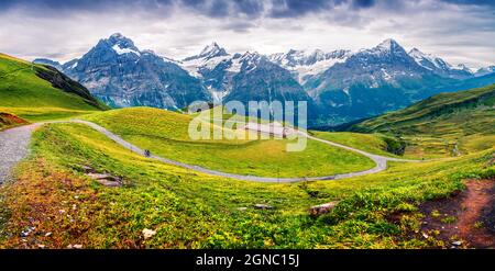 Dramatic summer panorama with a Grindelvald village in tha valley. Green morning view with a Mt. Schreckhorn and Wetterhorn on the background. Switzer Stock Photo