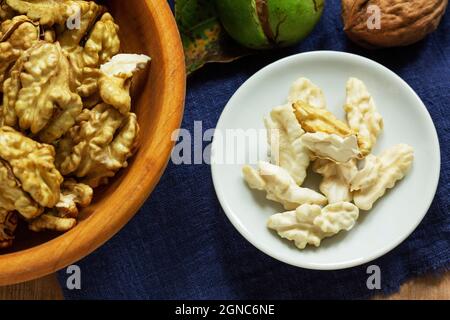 Young walnuts, shelled and in shell, walnut leaves. Rustic style. Stock Photo