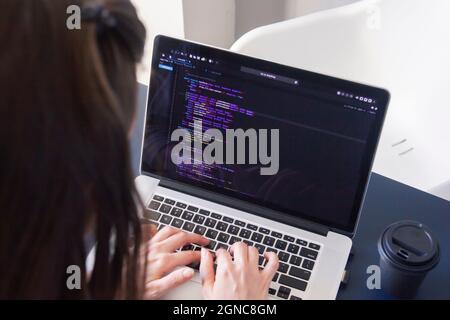 A programmer coding on a laptop in the workplace Stock Photo