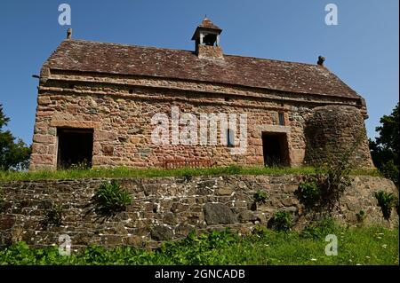 An exterior view of the medieval stone church building on top of a Neolithic burial mound at La Hogue Bie on the Island of Jersey. Stock Photo